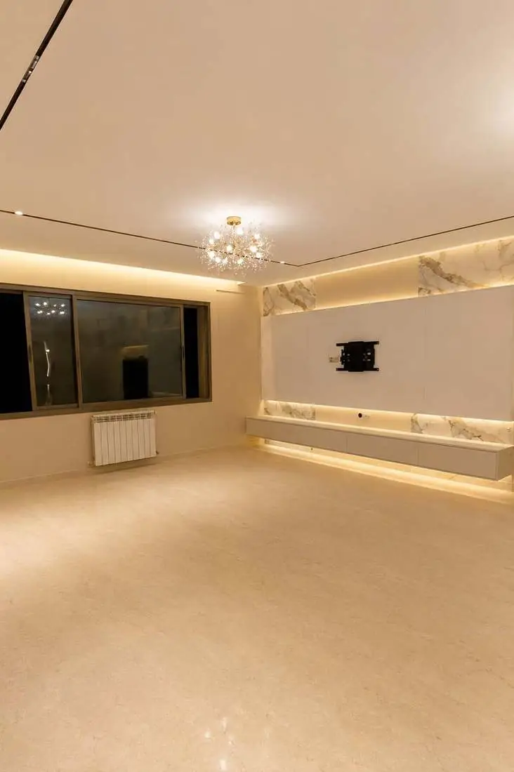 Salon terminé avec faux plafond, mur TV en marbre et éclairage LED